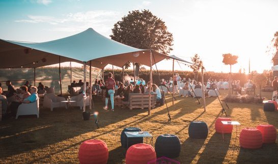 Zomerbar met stretchtenten en poefs bij zonsondergang